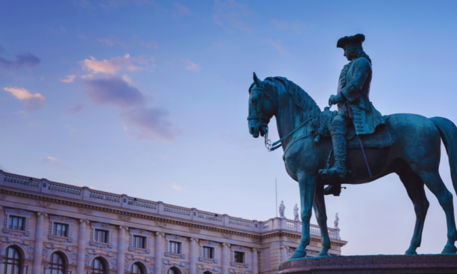 Large sculpture of a man riding a horse outside the art history museum in Vienna.