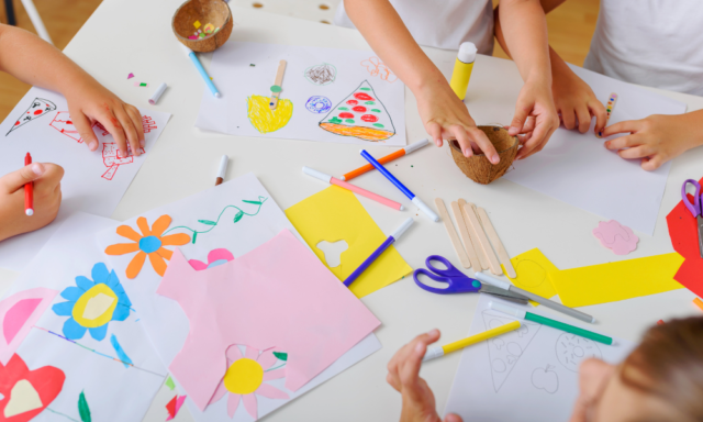 Overhead view of a craft table with children making art