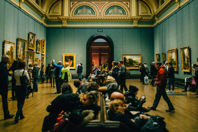 View of a classic museum gallery filled with paintings and visitors