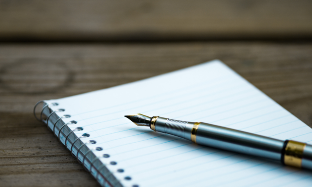 Blank spiral notebook with a fountain pen resting on it.