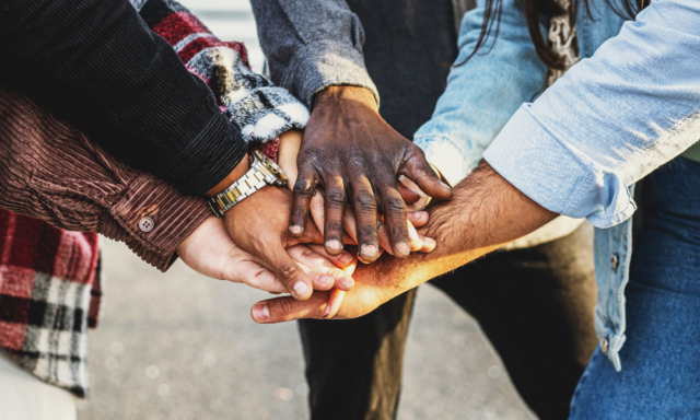 Diverse group of people stacking hands in a show of community