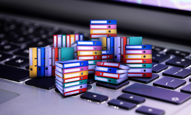 Rendering of miniature stacks of archive binders sitting atop a computer keyboard.