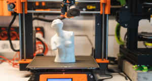 Tech Check-In: How Are Museums Using 3D Printers for Visitor Engagement Lately? an orange and black 3d printer printing a replica of a classical marble sculpture
