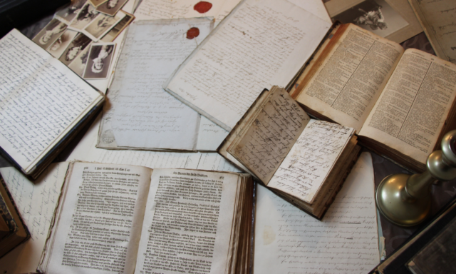 an assortment of old books and papers and photos on a table