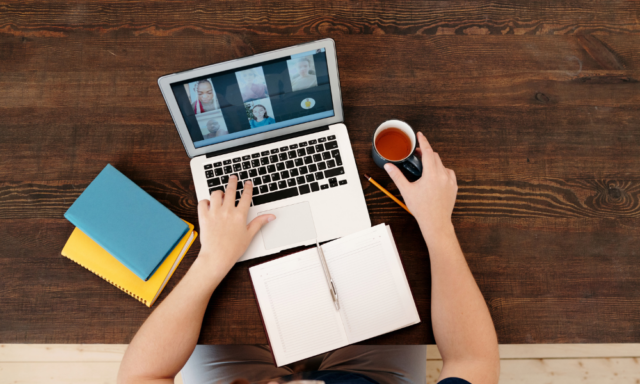 View from above of a person at a laptop with a notebook and a cup of coffee