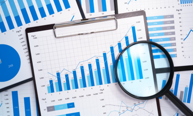 Papers showing data graphs and charts under a magnifying glass