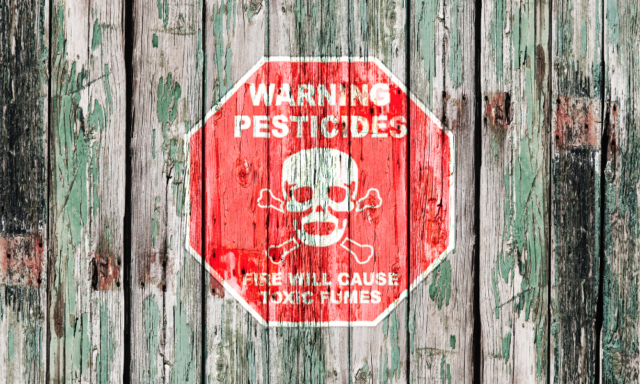 Red pesticide warning sign on a wooden fence