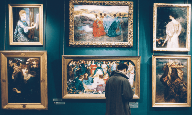 a person looking at paintings on display in an art museum