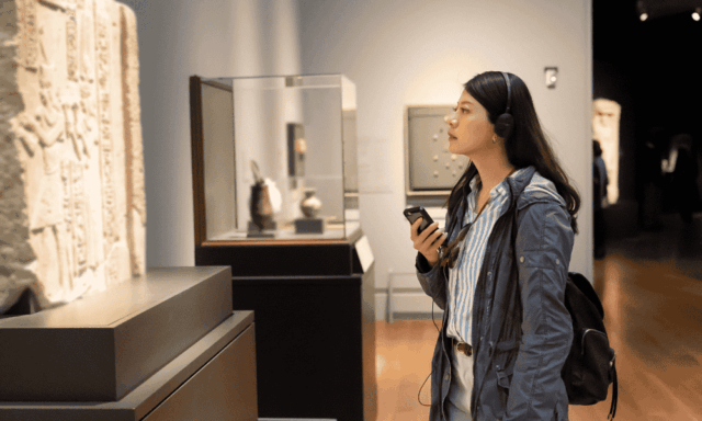 woman looking at objects in a museum while wearing headphones