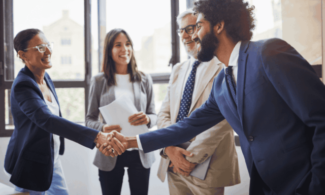 A group of people smiling and shaking hands in an office