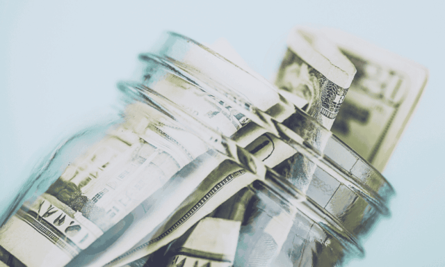 A glass jar with cash in it