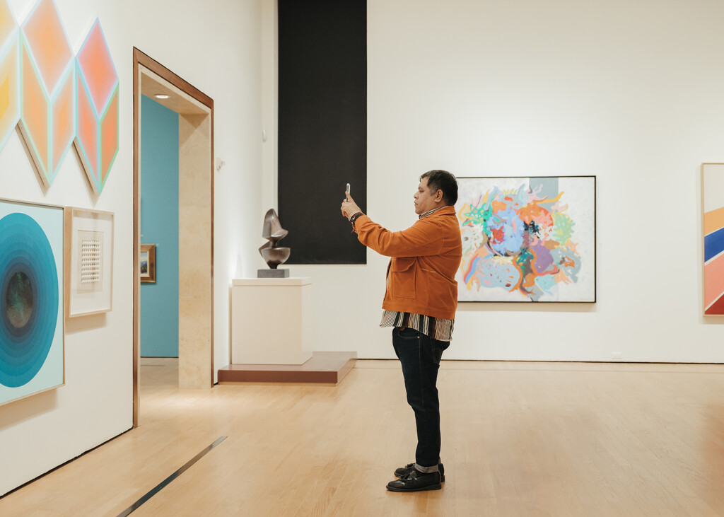 Man taking a photo of artwork at OKCMOA From the Vault exhibition