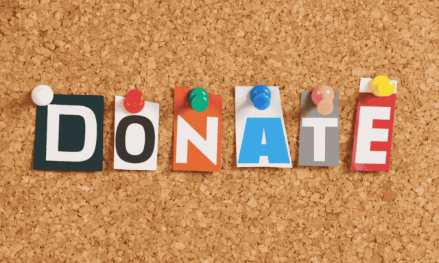 Letters cut from magazines and pinned to a corkboard spelling out "donate"