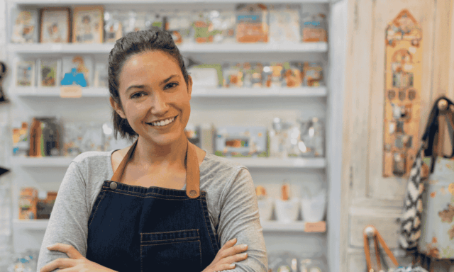 Woman shopkeeper standing in front of shelves of merch