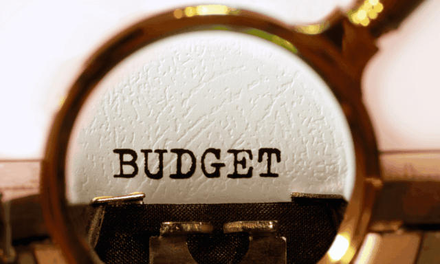 magnifying glass over the word "budget" typed on a typewriter