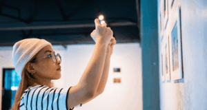 When Every Visitor Has a Camera: Designing Exhibitions That Promote Themselves Woman taking a photo of art on the wall at a museum