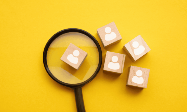 Magnifying glass and small wooden blocks stamped with people icons