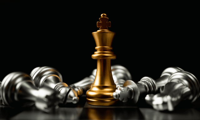 King chess piece surrounded by other fallen chess pieces